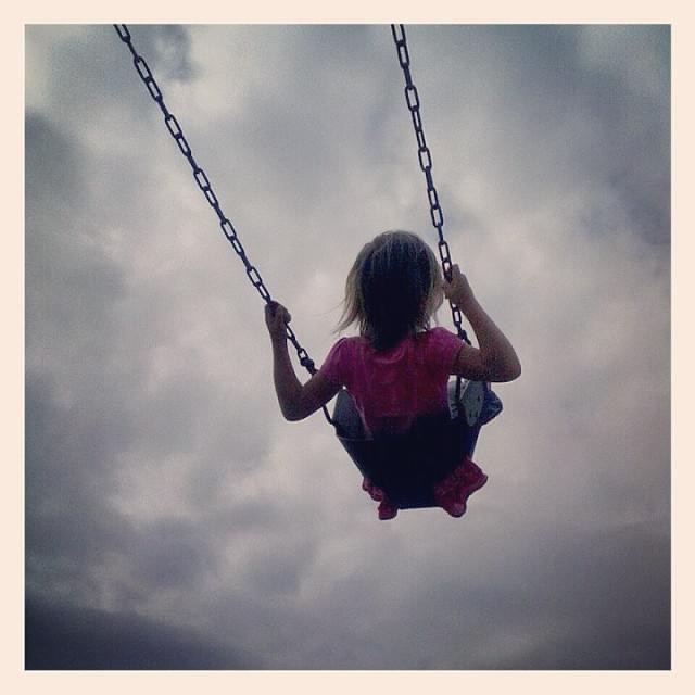Little girl with pink shirt on a swing